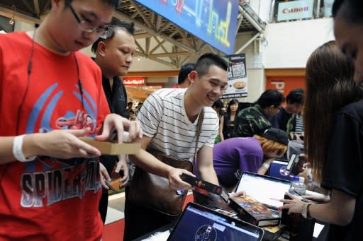 Fans collect newly released copies of Diablo III, the latest edition from the videogame franchise, during a launch event at a computer mall in Singapore on May 15, 2012. Thousands of people queud outside the mall, many of them taking time off from work or school to grab their copies. (AFP Photo/Simin Wang)