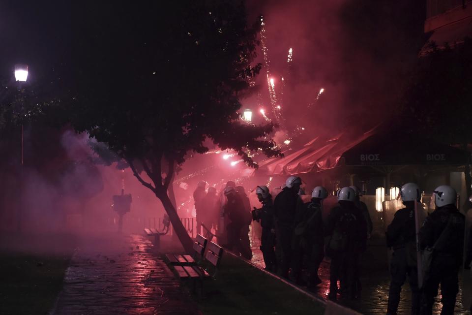 Riot police take cover as protesters throw fireworks during a rally in the northern Greek city of Thessaloniki, Friday, Dec. 14, 2018. Hundreds of people protest against government efforts to end a three-decade-old dispute with neighboring Macedonia as the Greek Prime Minister Alexis Tsipras delivered a speech to party cadres and supporters. (AP Photo/Giannis Papanikos)