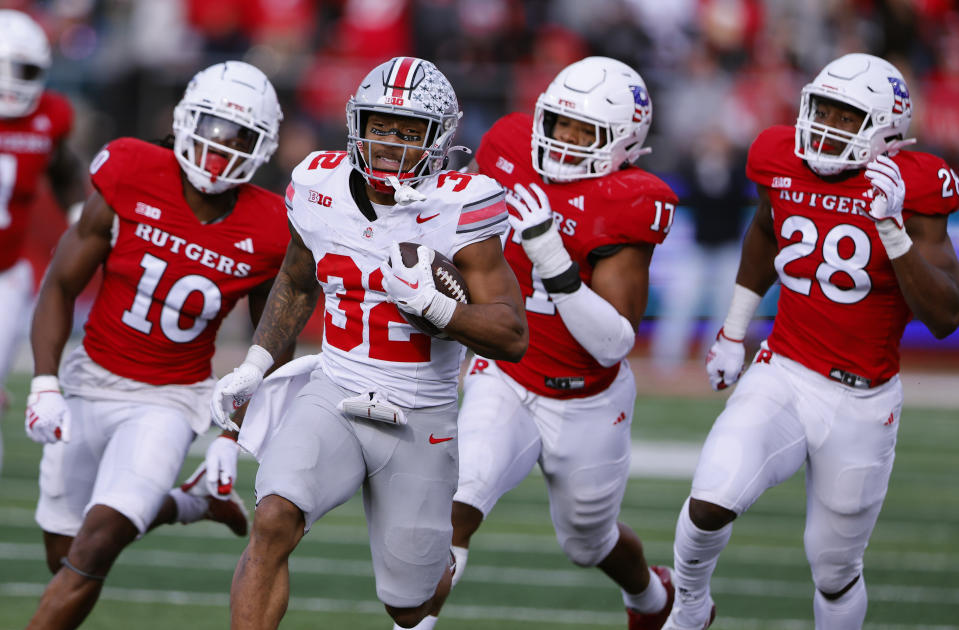 Ohio State running back TreVeyon Henderson (32) rushes for a first down ahead of Rutgers defensive back Flip Dixon (10), linebackers Deion Jennings (17) and Dariel Djabome (28) during the second half of a NCAA college football game, Saturday, Nov. 4, 2023, in Piscataway, N.J. Ohio State won 35-16. (AP Photo/Noah K. Murray)