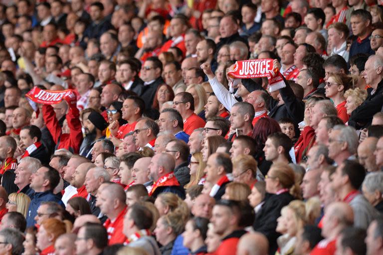 People hold up football scarves as they attend a memorial service to mark the 25th anniversary of the Hillsborough Disaster at Anfield Stadium in Liverpool, northwest England on April 15, 2014