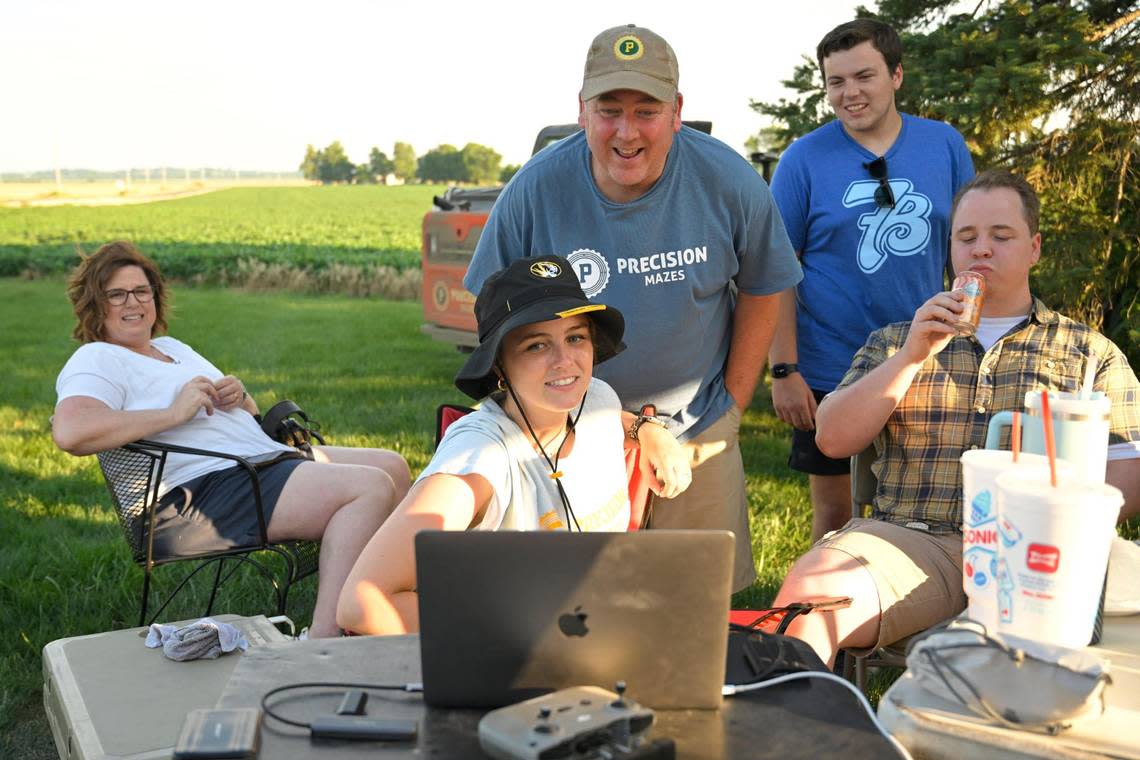 Rob Stouffer of Precision Mazes, center, looks over photos with members of his team including, from left, his wife, Rachel, daughter, Madeline McConnell at the computer, Connor O’Neal, a member of the design team, and son, Bennett Stouffer, an engineer who assists with technical issues, after he cut a welcome message to Taylor in a field of wheat stubble on Monday, July 3, 2023, in Orrick, Missouri.