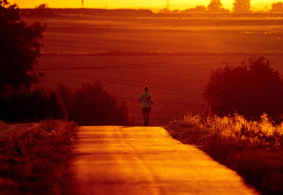 FILE - A man uses cool morning hours for a run on a small road in the outskirts of Frankfurt, Germany, Monday, July 18, 2022. Rising global temperatures are elevating air conditioning from a luxury to a necessity in many parts of Europe, which long has had a conflictual relationship with energy-sucking cooling systems deemed by many a U.S. indulgence. (AP Photo/Michael Probst, file )