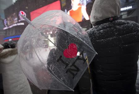 A couple stands in the falling snow in Times Square in New York, January 26, 2015. REUTERS/Mike Segar