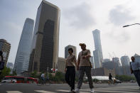 Pedestrians cross an intersection with the background of the central business district in Beijing, China, Monday, July 15, 2024. China's ruling Communist Party is starting a four-day meeting Monday that is expected to lay out a strategy for self-sufficient economic growth in an era of heightened national security concerns and restrictions on access to American technology. (AP Photo/Vincent Thian)