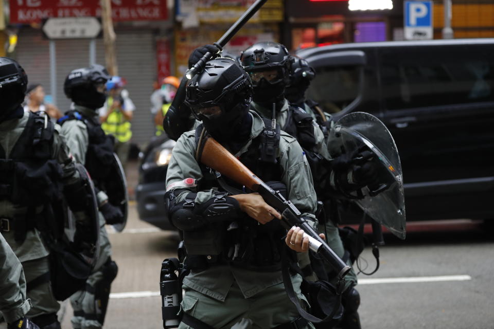 Police prepare to fire tear gas at protestors in Hong Kong, Sunday, Oct. 6, 2019. Shouting "Wearing mask is not a crime," tens of thousands of protesters braved the rain Sunday to march in central Hong Kong as a court rejected a second legal attempt to block a mask ban aimed at quashing violence during four months of pro-democracy rallies. (AP Photo/Vincent Thian)