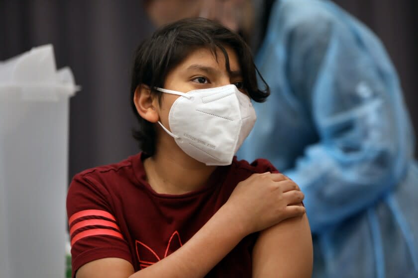 San Pedro—May 24, 2021—Max Hernandez, age 12, gets vaccinated by Aida Flores, a visiting nurse from Austin, Texas, on May 24, 2021. San Pedro Senior High school is one of the Los Angeles County Unified schools providing coronavirus vaccines for children 12 and up. (Carolyn Cole / Los Angeles Times)