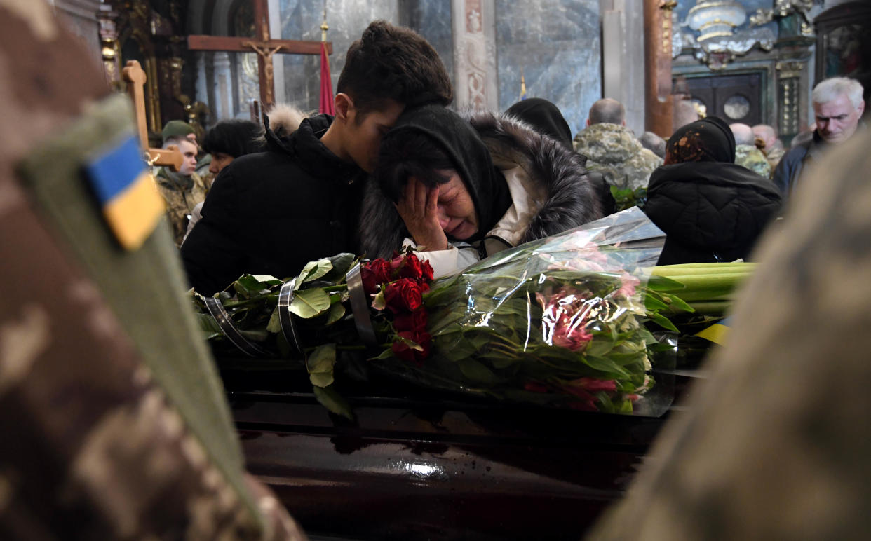 Crying family members stand near a casket.