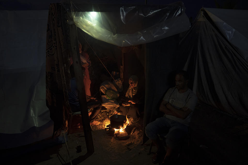 Palestinians displaced by the Israeli bombardment of the Gaza Strip sit by a fire in a UNDP-provided tent camp in Khan Younis, Wednesday, Nov. 1, 2023. (AP Photo/Fatima Shbair)