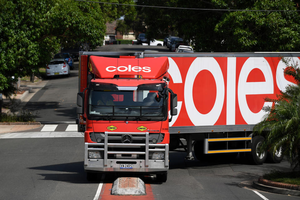 A Coles delivery truck driving up a street. 