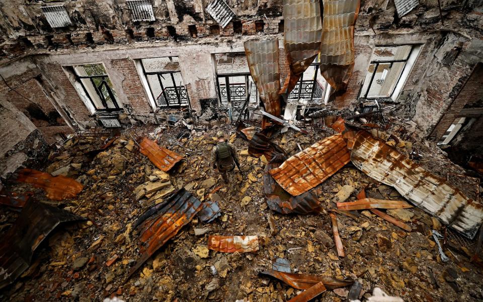 A soldier walks amongst the rubble of what was once a school in the devastated city of Lyman - Zohra Bensemra/Reuters