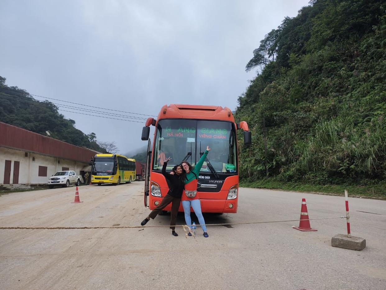 Two women posing in front of a bus in Southeast Asia