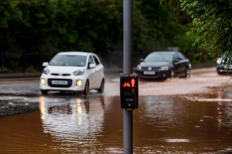 Two cars driving through a deep puddle of rainwater