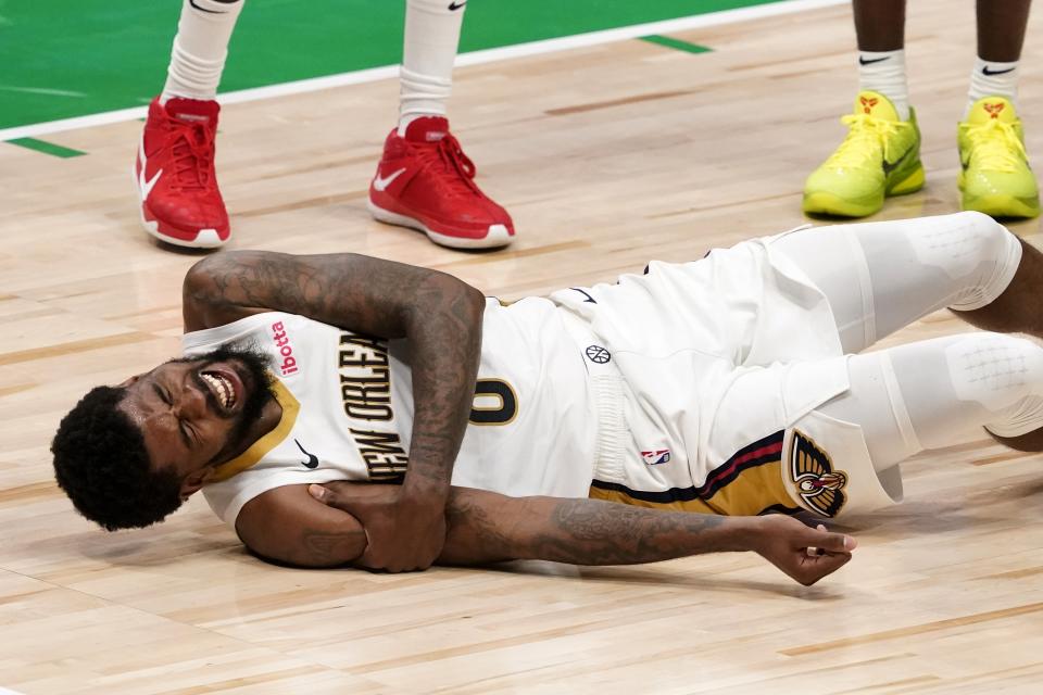 New Orleans Pelicans forward Naji Marshall rolls on the court while holding on to his right arm after colliding with Dallas Mavericks' Dorian Finney-Smith during the second half of an NBA basketball game in Dallas, Wednesday, May 12, 2021. Marshall left the game. (AP Photo/Tony Gutierrez)