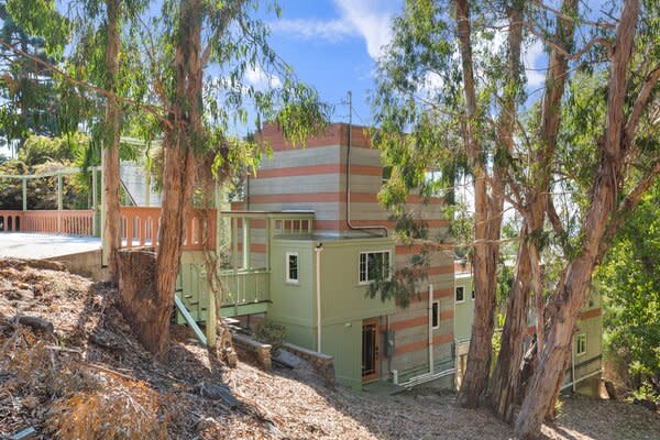 The colorful multi-story home sits nestled into a hillside overlooking the Bay. Soaring Eucalyptus trees surround the property, enhancing the overall sense of privacy.