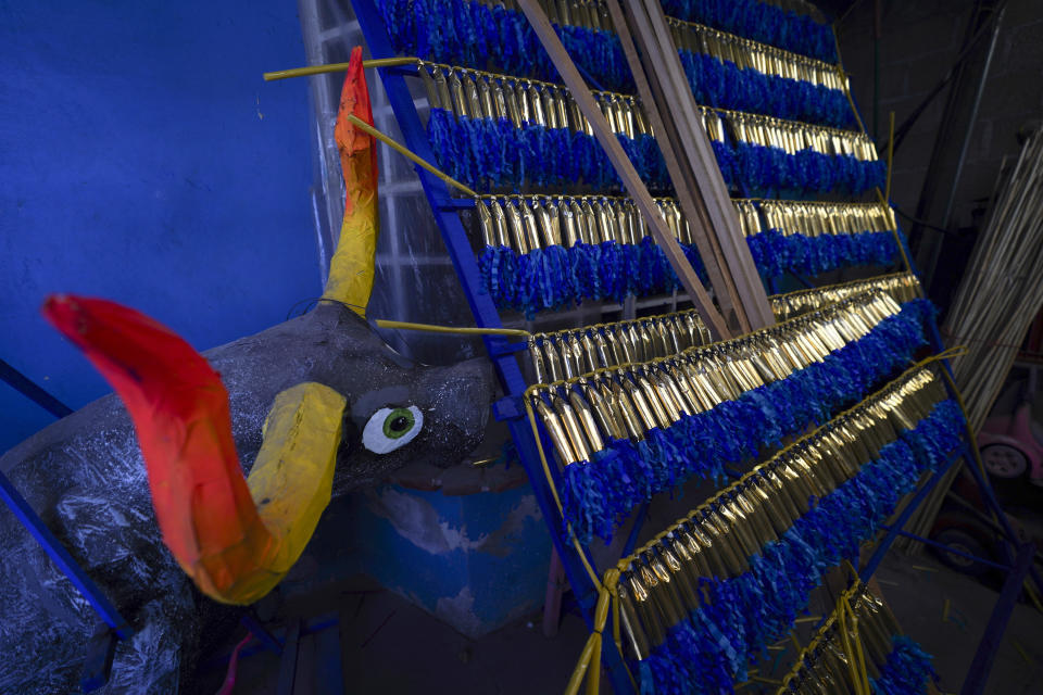 A paper-mache bull sits alongside strings of fireworks in a warehouse ahead of the annual festival honoring Saint John of God, the patron saint of the poor and sick whom fireworks producers view as a protective figure, in Tultepec, Mexico, Thursday, March 7, 2024. (AP Photo/Marco Ugarte)