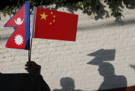 A Nepalese man holds Chinese and Nepalese flags as he waits to welcome Chinese president Xi Jinping in Kathmandu, Nepal, Saturday, Oct 12, 2019. Xi arrived Saturday from New Delhi, where he met with Indian Prime Minister Narendra Modi. He was received by Nepalese President Bidhya Devi Bhandari and Prime Minister K.P. Sharma Oli at the Kathmandu airport. (AP Photo/Niranjan Shrestha)