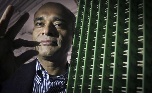 In this Thursday, Dec. 20, 2012, photo, Chet Kanojia, founder and CEO of Aereo, Inc., stands next to a server array of antennas as he holds an antenna between his fingers, in New York.  Aereo is one of several startups created to deliver traditional media over the Internet without licensing agreements. Past efforts have typically been rejected by courts as copyright violations. In Aereoâ€™s case, the judge accepted the companyâ€™s legal reasoning, but with reluctance. (AP Photo/Bebeto Matthews)