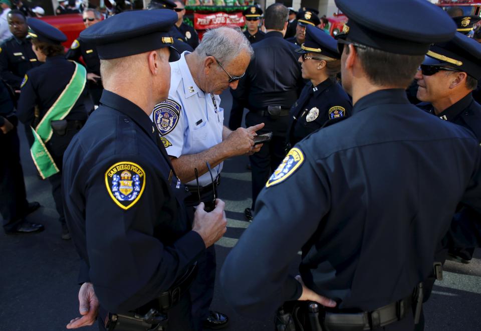 Retired Senior Volunteer Patrol administrator Robert Stewart (C) checks messages on his phone as he attends the city's annual St. Patrick's Day Parade with San Diego Police Officers in San Diego, California, United States March 14, 2015. (REUTERS/Mike Blake)