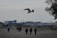 Migrants walk near a camp in Calais, northern France, Thursday, Oct. 14, 2021. While some migrants with money can pay to go to Britain on flimsy, overcrowded boats in often dangerous waters, the ones who can’t have to jump on one of the tens of thousands commercial trucks that pass each week between France and Britain. (AP Photo/Christophe Ena)