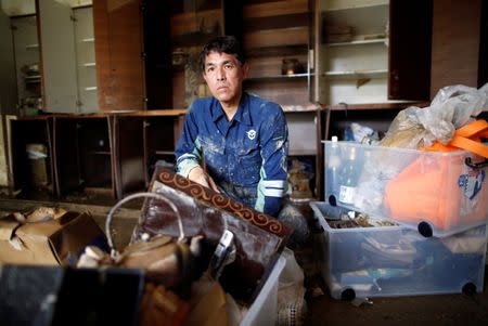 51-year-old Kairyu Takahashi, an Okayama prefectural assemblyman, tries to remove mud and debris from his house in a flood affected area in Mabi town in Kurashiki, Okayama Prefecture, Japan, July 12, 2018. REUTERS/Issei Kato