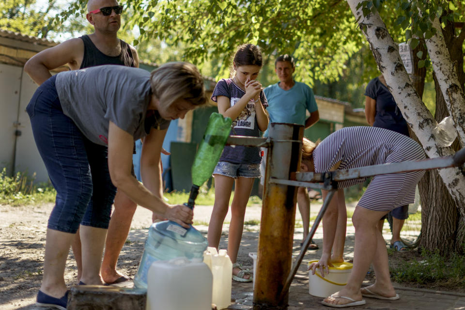 FILE - Residents gather to pump water from a well outside an apartment complex in Sloviansk, Donetsk region, eastern Ukraine, on Aug. 6, 2022. Fighting between Ukrainian and Russian forces near the key city has damaged vital infrastructure that has cut residents off from gas and water for months. According to Russian state TV, the future of the Ukrainian regions occupied by Moscow's forces is all but decided: Referendums on becoming part of Russia will soon take place there, and the joyful residents who were abandoned by Kyiv will be able to prosper in peace. In reality, the Kremlin appears to be in no rush to seal the deal on Ukraine's southern regions of Kherson and Zaporizhzhia and the eastern provinces of Donetsk and Luhansk.(AP Photo/David Goldman)