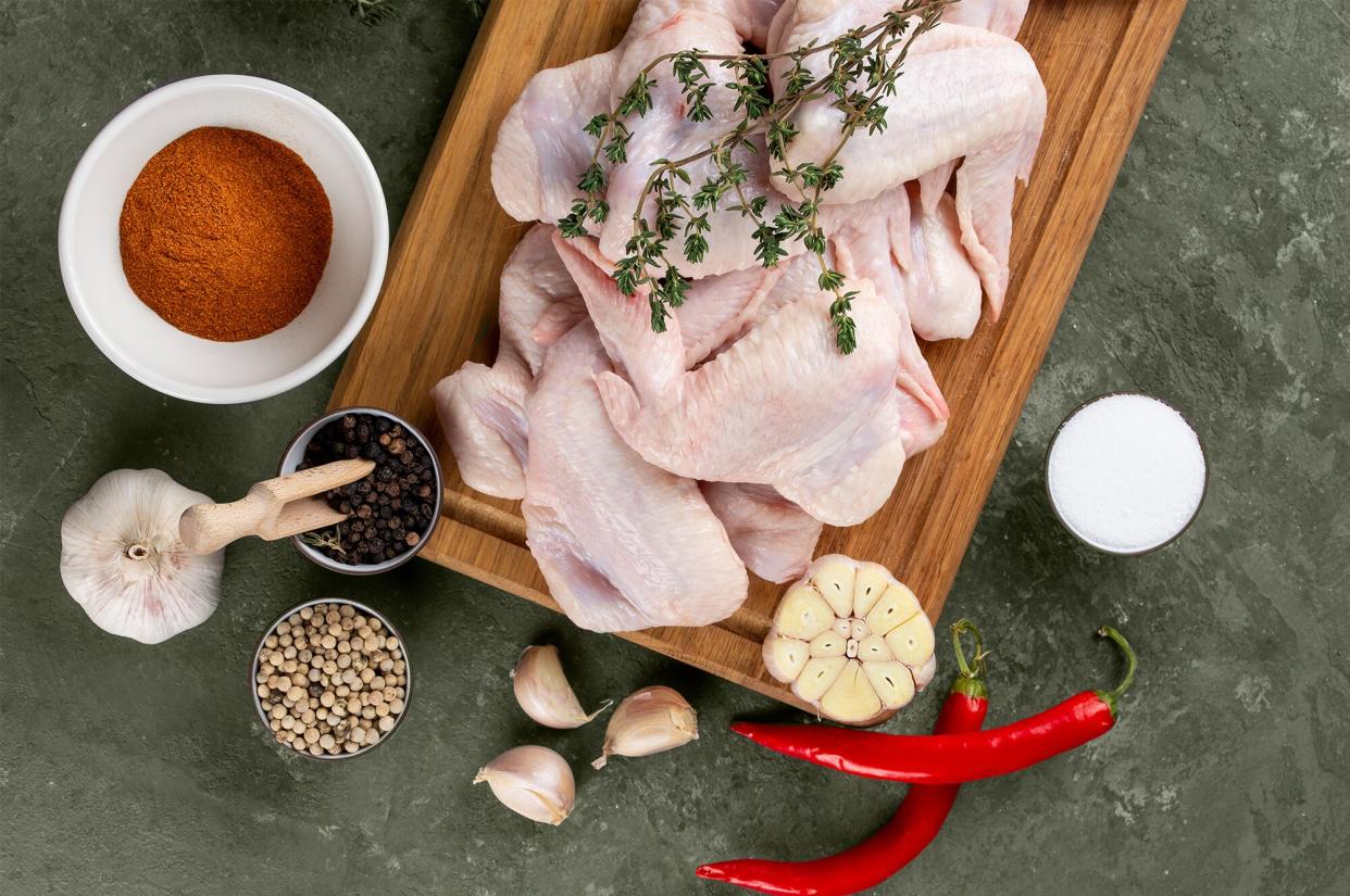 Raw chicken on cutting board surrounded by ingredients