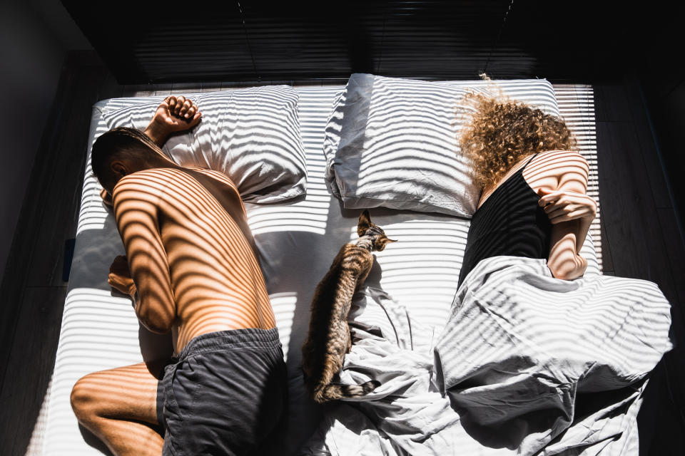 Two people lying in a bed facing away from each other