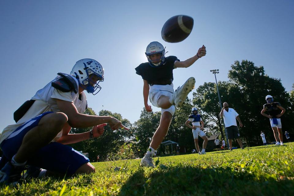 QB Evan Lamontagne holds the ball for Jackson Dane as he kicks during the Fairhaven High School football team practice held at Cushman Park in Fairhaven.