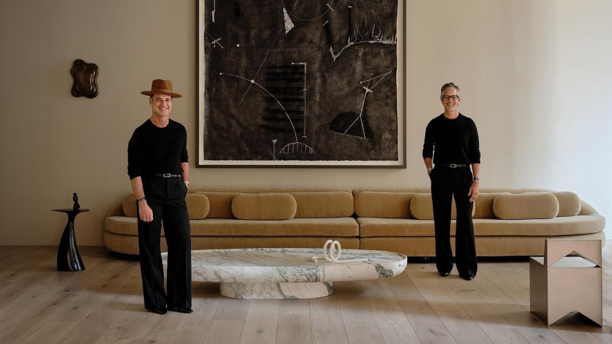 a couple of men standing in front of a large painting