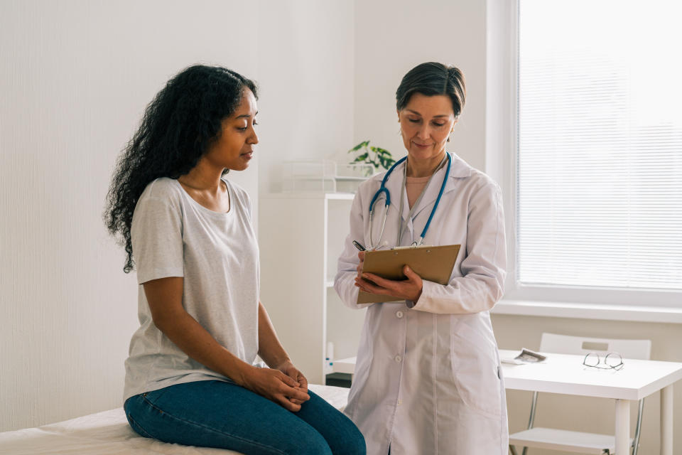 A doctor is talking to a patient who is sitting on an examination table in a medical office