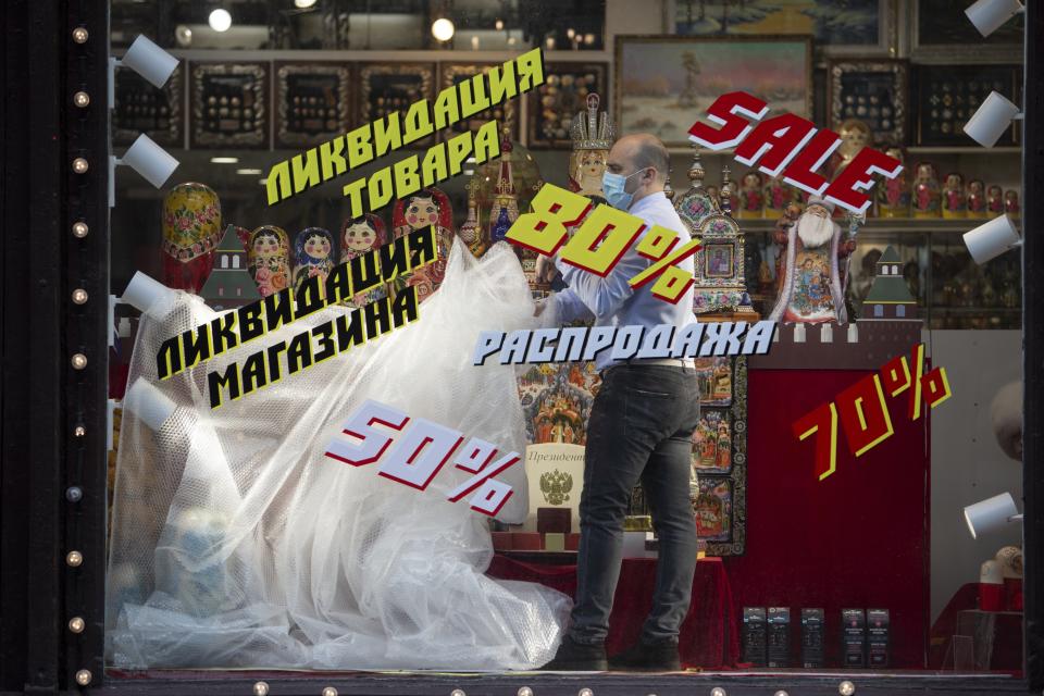 An employee removes a plastic cover from goods at the shop window after reopening in Moscow, Russia, on Monday, June 1, 2020. Monday's reopening of retail stores along with dry cleaners and repair shops comes as the pace of contagion has stabilized in the Russian capital that has accounted for about half of the nation's infections. (AP Photo/Alexander Zemlianichenko Jr)