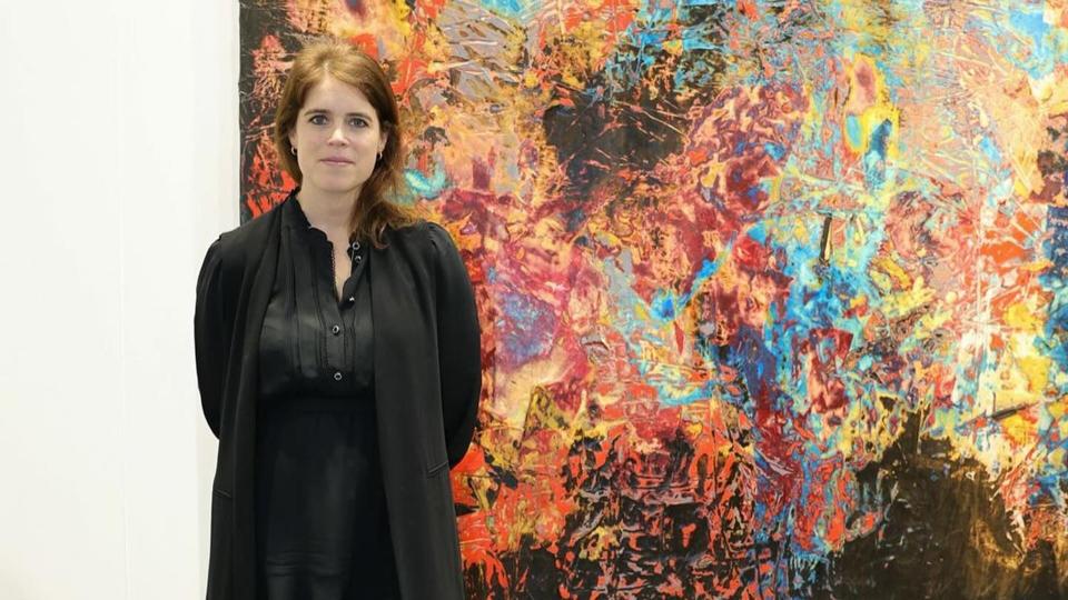 Princess Eugenie poses in a black dress in front of a creative painting