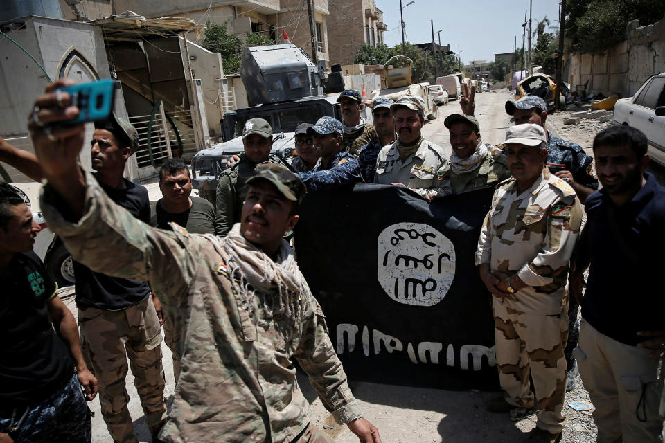 Iraqi Army members pose with an Islamic State flag