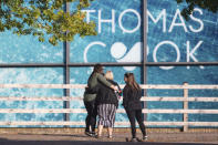 People gather outside the headquarters of tour operator Thomas Cook, in Peterborough, England, which has ceased trading with immediate effect after failing in a final bid to secure a rescue package from creditors Monday Sept. 23, 2019. British tour company Thomas Cook collapsed early Monday after failing to secure emergency funding, leaving tens of thousands of vacationers stranded abroad. The British government said the return of the 178-year-old firm's 150,000 British customers now in vacation spots across the globe would be the largest repatriation in its peacetime history. (Joe Giddens/PA via AP)
