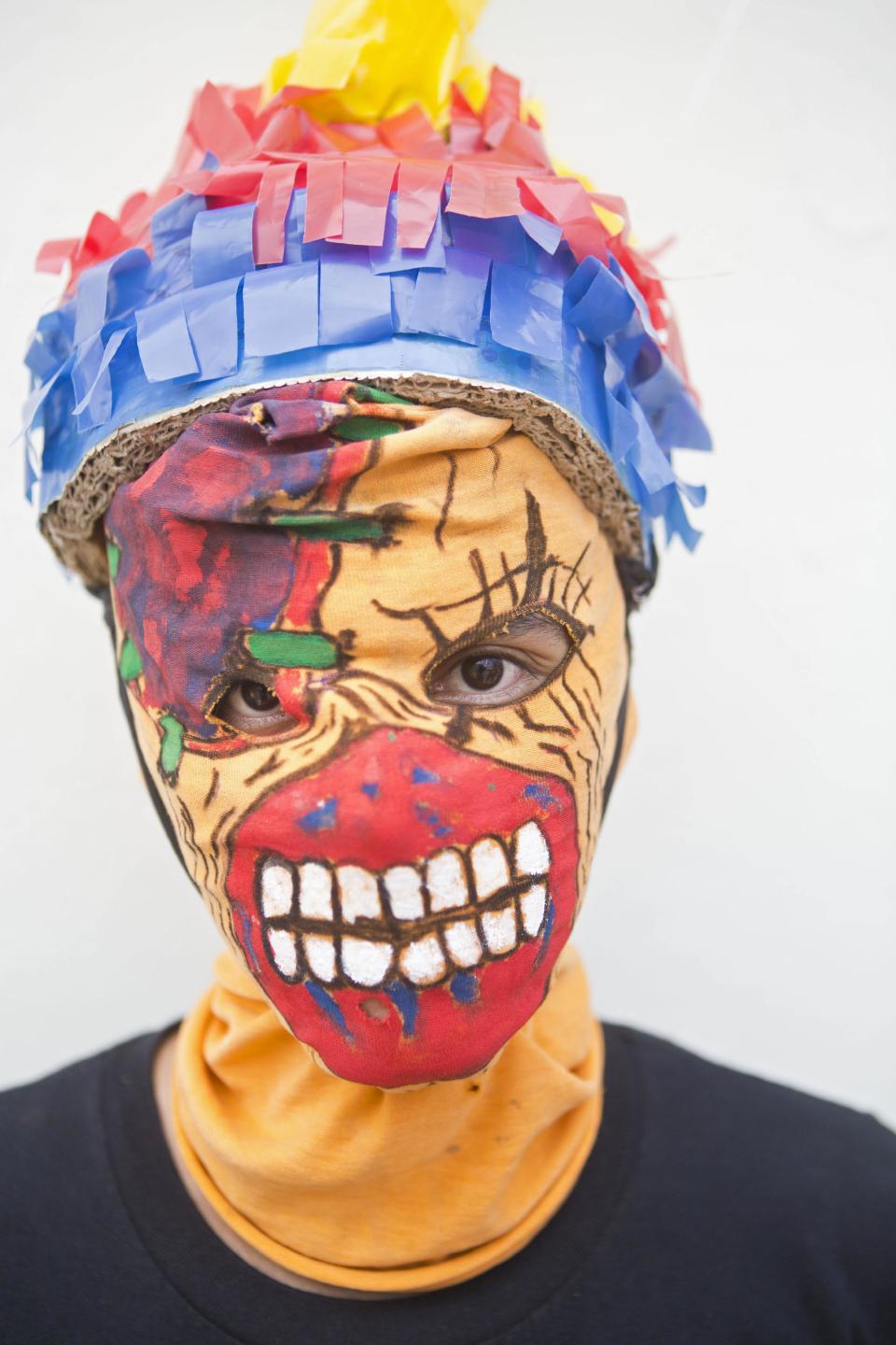 En imagen del 18 de abril de 2014 un joven enmascarado que representa a "Judas" posa para una fotografía durante un momento de descanso de la procesión llamada "Los Encadenados" que se lleva a cabo en la ciudad de Masatepe, Nicaragua. Más de 900 personas participaron en la procesión de este año, algunos para mentener viva la tradición y otros para pagar promesas religiosas. (Foto de AP/Esteban Felix)