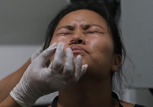 A health worker takes a nasal swab sample from a woman. Nova Scotia reported 34 new cases of COVID-19 on Friday. (Yirmiyan Arthur/The Associated Press - image credit)