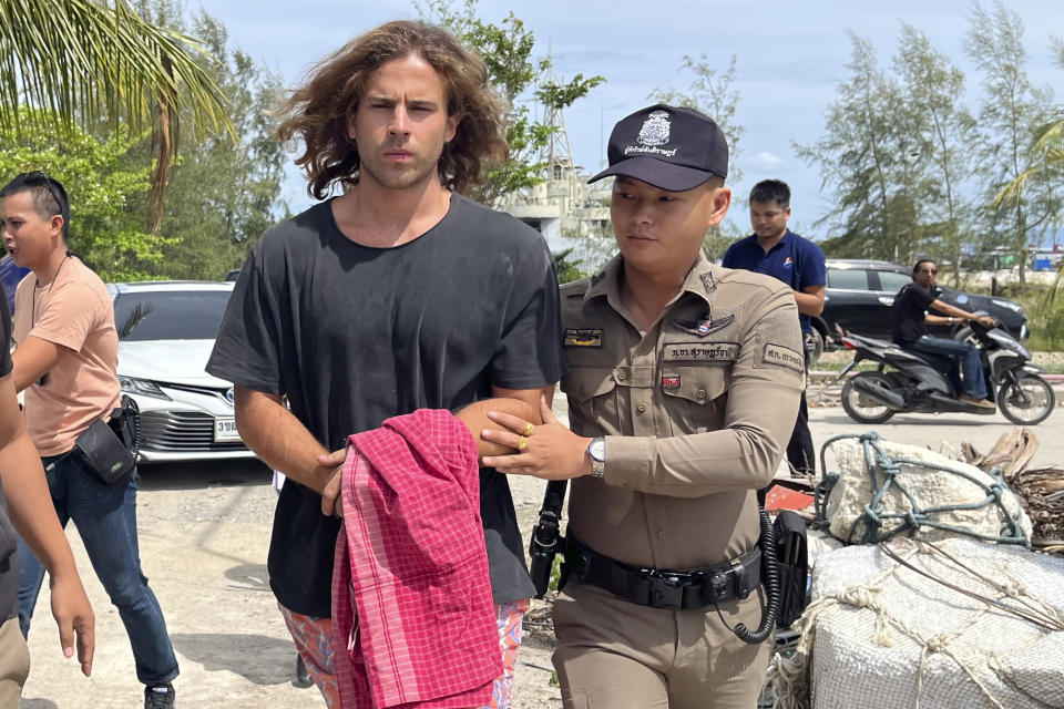 FILE - A Thai police officer escorts Spanish Daniel Sancho Bronchalo on suspicion of murdering and dismembering a Colombian surgeon from Koh Phagnan island to Koh Samui Island court, southern Thailand, Monday, Aug. 7, 2023. Thailand's Koh Samui Provincial court Tuesday, April 9, 2024, began a trial on the son of a Spanish actor accused of murdering and dismembering the surgeon on the popular tourist island. (AP Photo/Somkeat Ruksaman, File)