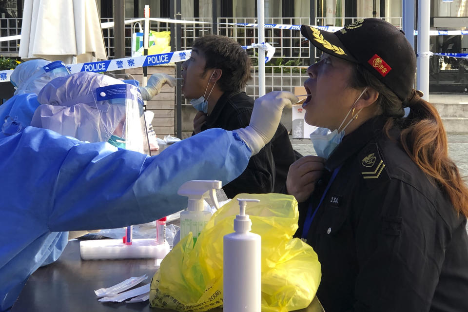 A medical worker collects sample swab sample from residents in a lockdown area in the Jingan district of western Shanghai, Monday, April 4, 2022. China has sent more than 10,000 health workers from across the country to Shanghai, including 2,000 military medical staff, as it struggles to stamp out a rapidly spreading COVID-19 outbreak in China's largest city. (AP Photo/Chen Si)