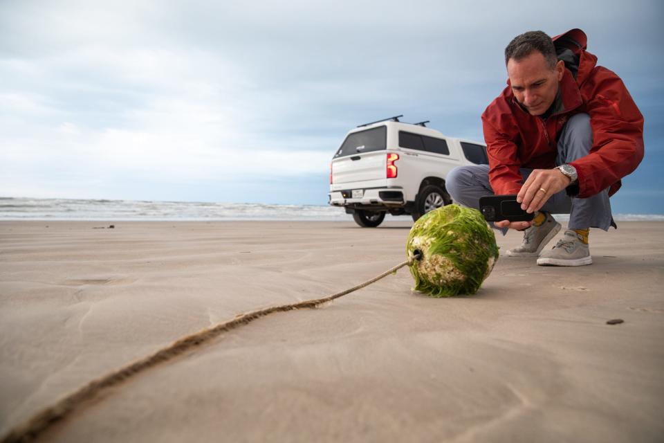 While combing the beach, Jace Tunnell, a marine biologist with Harte Research Institute, stops to photograph a buoy that washed ashore at Padre Island National Seashore on Tuesday, March 19, 2024, in Corpus Christi, Texas.