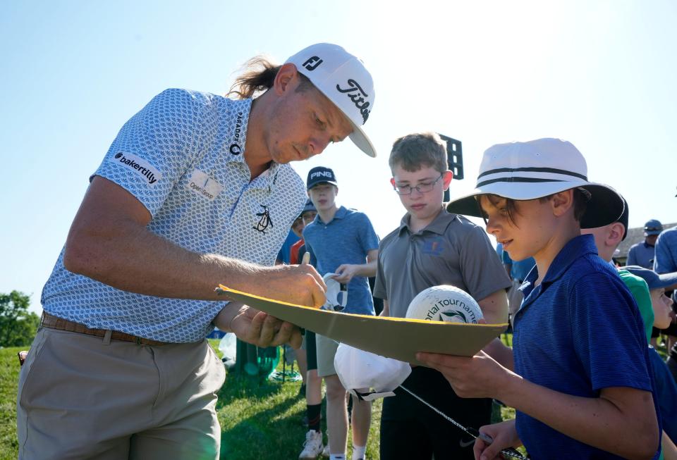 Professional golfer Cameron Smith signs a yellow pin flag for Camden Maher, 9, of Dublin, during the Golden Bear Pro-Am Wednesday at the Memorial Tournament held at Muirfield Village Golf Club in Dublin.