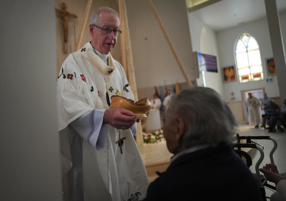 Edmonton Archbishop Richard Smith gives communion during the rededication ceremony and Sunday Mass at Sacred Heart Church of the First Peoples, July 17, 2022, in Edmonton, Alberta. In 2020, the church was damaged in a large fire and has now been renovated ahead of Pope Francis' visit to the Canadian province. (AP Photo/Jessie Wardarski)