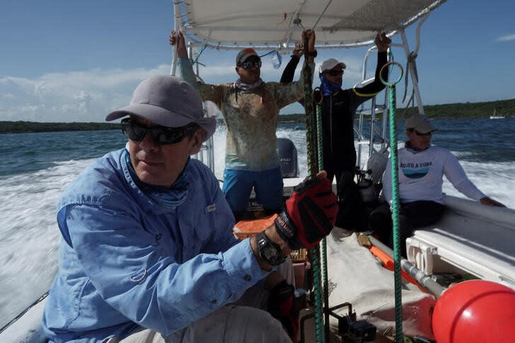 Fabián Pina, un biólogo marino y uno de los líderes del proyecto expedicionario "Bojeo a Cuba", se prepara para liberar cámaras con el fin de fotografiar tiburones frente a la costa de Cienfuego