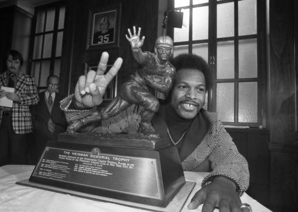 Archie Griffin of Ohio State holds up two fingers as he poses with the Heisman Trophy.