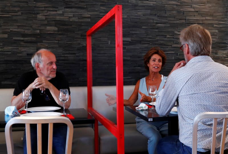People test a protective plexiglass barrier in a restaurant in Brussels