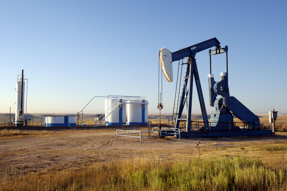 An oil pump next to some storage tanks.