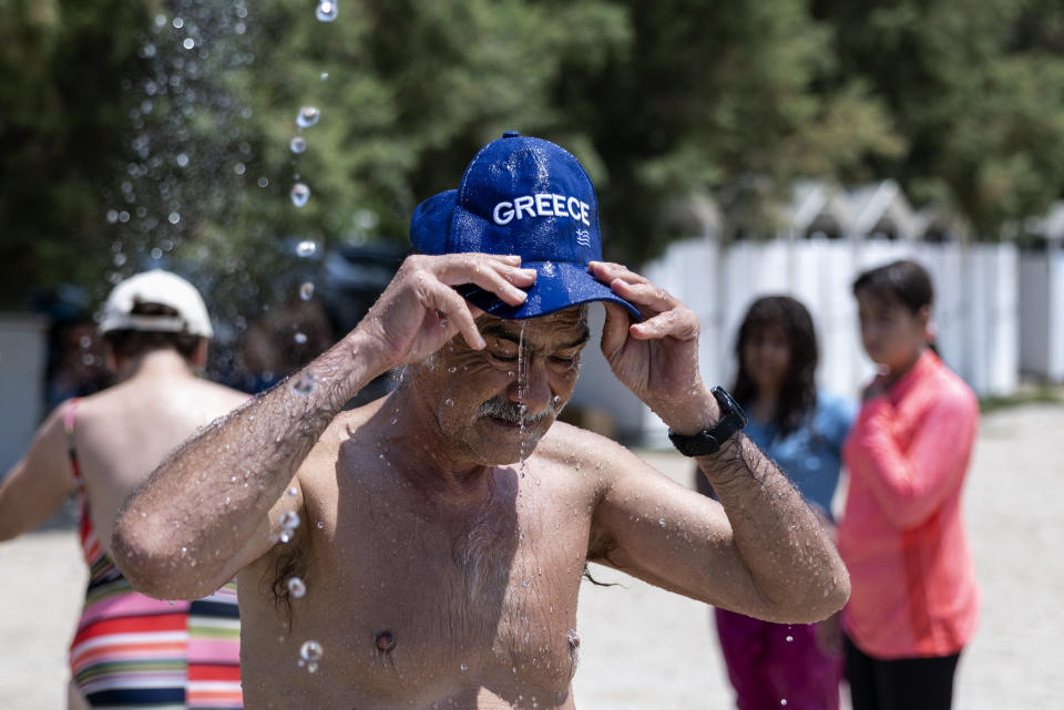 A swimmer cools himself at a shower at Alimos suburb, in Athens, Greece, Saturday, July 15, 2023. Temperatures reached up to 42 degrees Celsius in some parts of the country, amid a heat wave that continues to grip southern Europe. (AP Photo/Yorgos Karahalis)