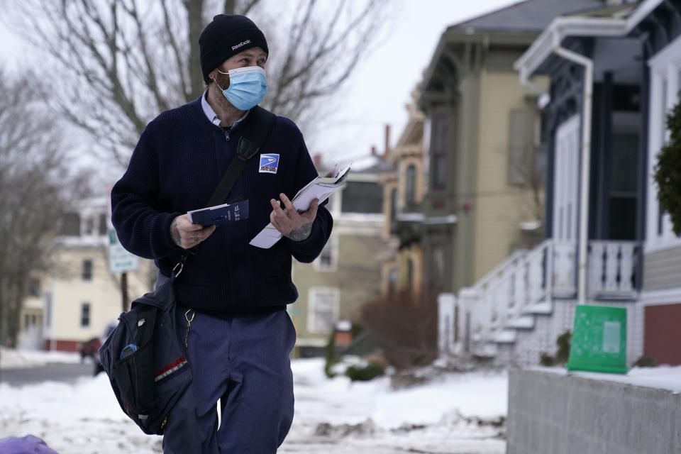 Postal carrier Josiah Morse makes his rounds, Wednesday, Feb. 3, 2021, in Portland, Maine. The U.S. Postal Service's stretch of challenges didn't end with the November general election and tens of millions of mail-in votes. The pandemic-depleted workforce fell further into a hole during the holiday rush, leading to long hours and a mountain of delayed mail. (AP Photo/Robert F. Bukaty)