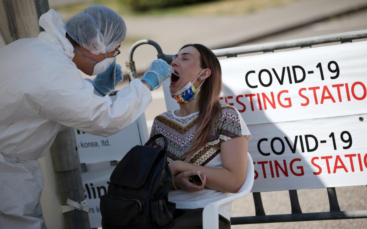 A health worker takes a swab from a woman at a mobile testing station for coronavirus disease in Almaty, Kazakhstan - Pavel Mikheyev/Reuters 