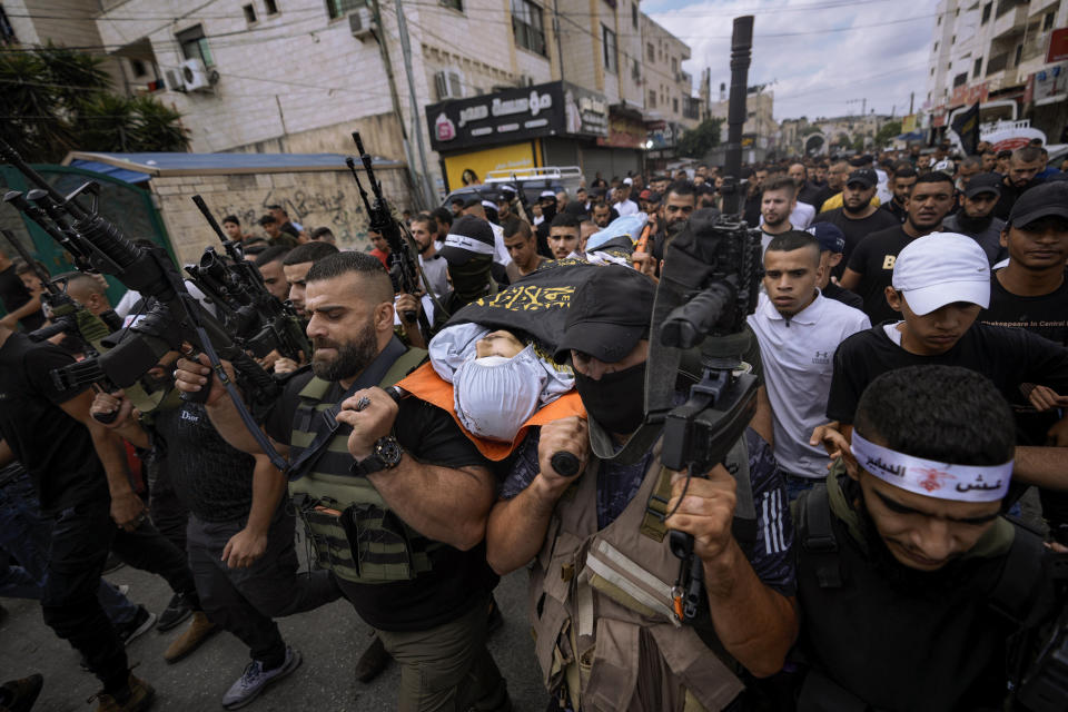 Armed Palestinians carry the body of Mahmoud Al-Sous, covered with a flag of the Islamic Jihad militant group during his funeral in the West Bank town of Jenin, Saturday, Oct. 8, 2022. (AP Photo/ Majdi Mohammed)