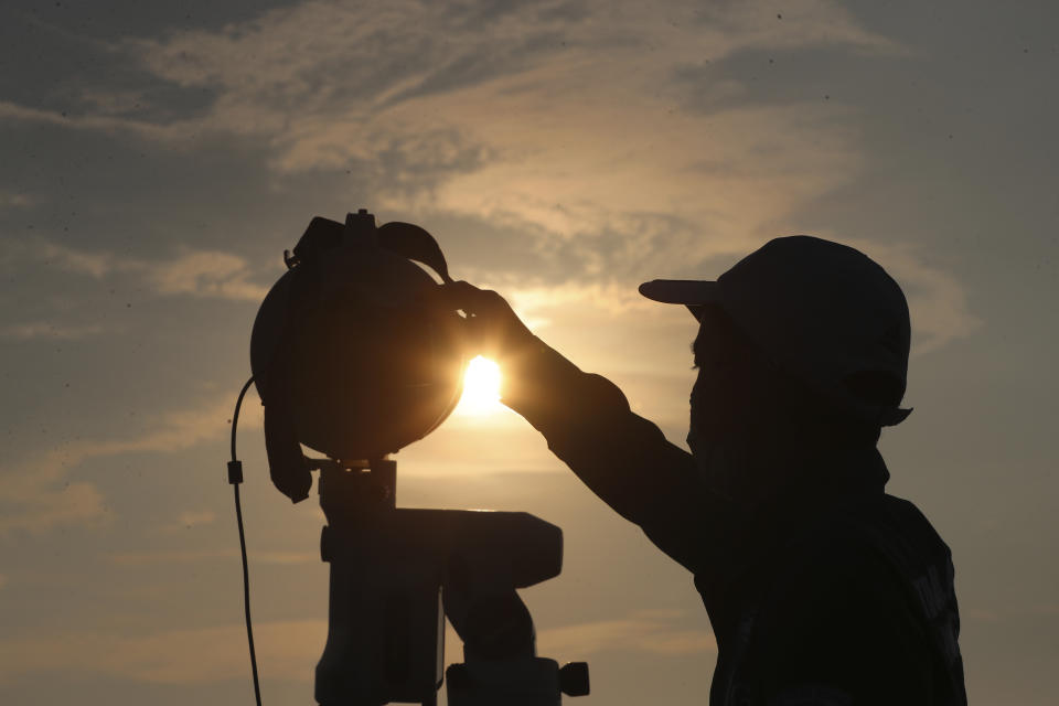 An official is silhouetted as he uses a telescope to scan the horizon for a crescent moon that will determine the beginning of the holy fasting month of Ramadan in Jakarta, Indonesia, Monday, April 12, 2021.(AP Photo/Achmad Ibrahim)